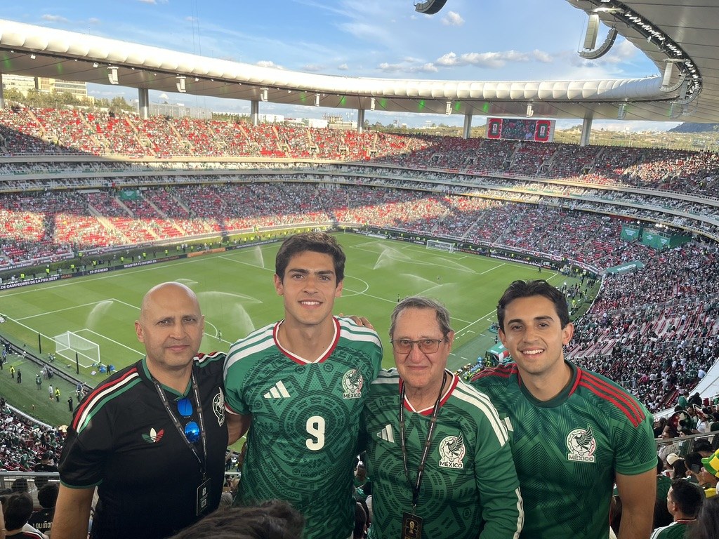 Fabian with family at a soccer stadium, all wearing Mexico green jerseys.